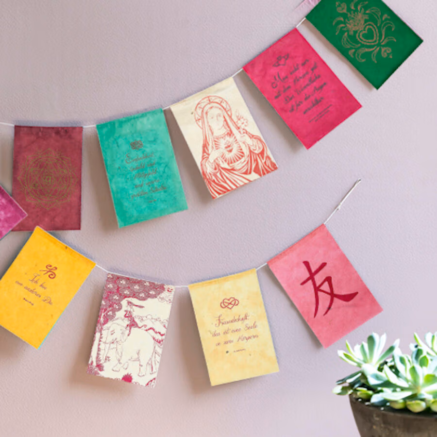 Wensvlaggetjes uit Nepal met Nederlandse tekst gemaakt van fairtrade geschept papier met verschillende kleuren en thema's. De wensvlaggetjes zijn als wenskaart te versturen met briefpapier en enveloppe. Er zitten 5 vlaggetjes per slinger en de vlaggetjes zijn 10 bij 15 centimeter groot.