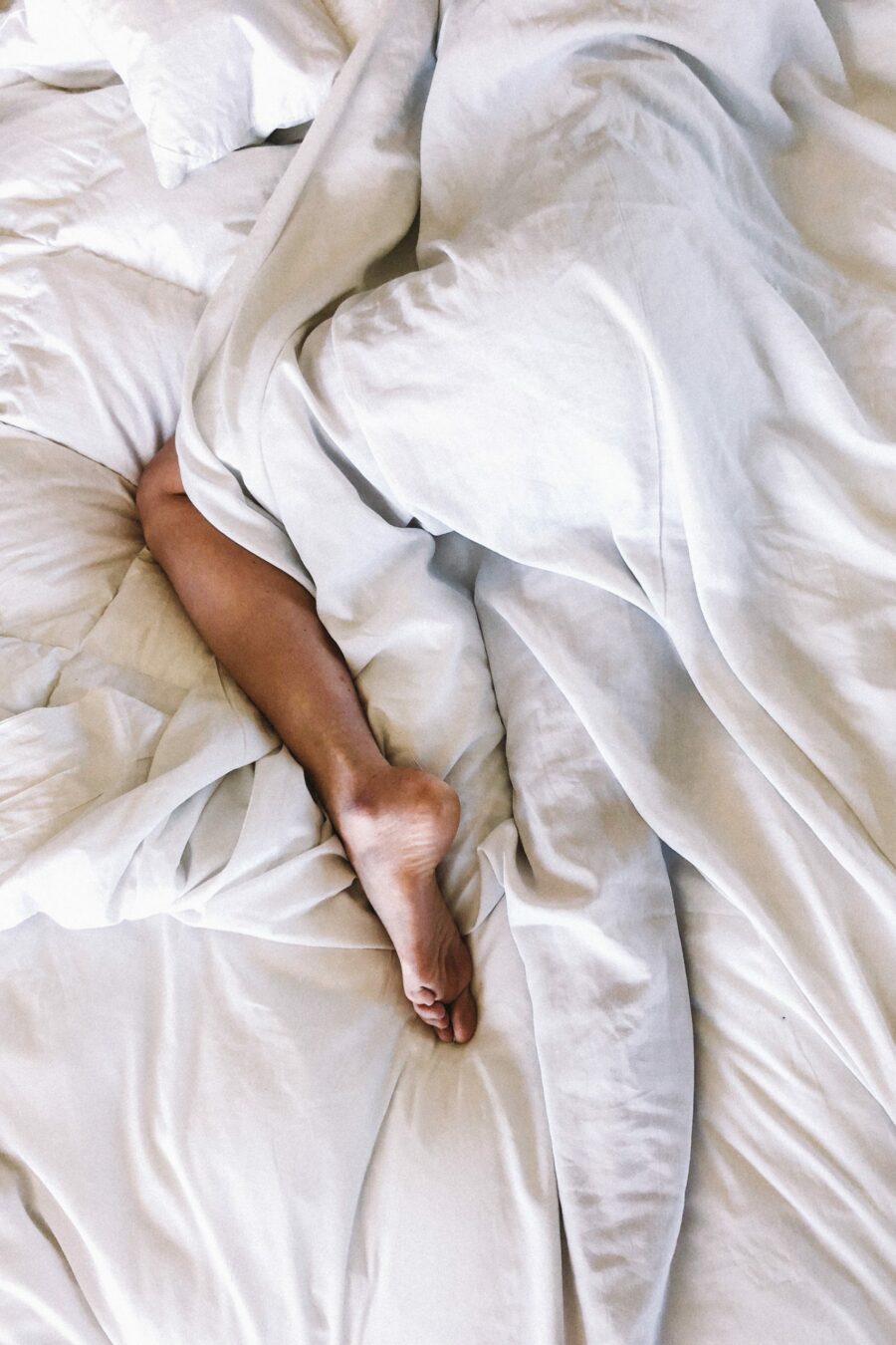 Een ontspannen persoon ligt in bed met fris wit beddengoed en geniet van de slaap producten van Tribe of Awareness. De Organic en duurzame materialen van de producten zorgen voor een rustgevende en comfortabele nachtrust. De slaap producten van Tribe of Awareness bieden de ideale ondersteuning voor een goede nachtrust en dragen bij aan een uitgeruste start van de dag.
