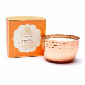 Verlicht je pad naar innerlijke harmonie met deze luxe kokosboter/sojawas geurkaars. De kaars is met de hand gegoten met 2 lonten in een prachtige verkoperde metalen pot, doordrenkt met het goede van Ayurvedische essentiële oliën. Deze grondende melange van heilige salie is zuiverend, terwijl de verkoelende eigenschappen van munt opladen en verkwikken. Past het beste bij mensen met kapha dosha. De geurkaars brand wel 20 uur.