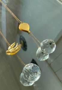 Raamkristal hangend in een kamer, reflecterend natuurlijk licht en creërend een kleurrijk regenboog effect.