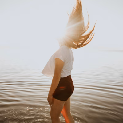 Vrouw staat tot haar enkels in de zee en geniet van de ontspannende werking van magnesiumrijk zeewater op de huid.