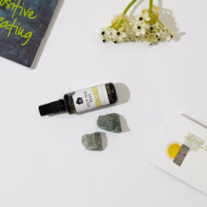 Rock Your World Be Happy Spray in een glazen flesje met een wit en geel label waar Be Happy spray op staat.