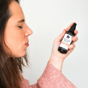 Hanneke Peeters de founder van Rock Your World zit met haar ogen dicht en sprayt Be Fresh spray uit een flesje met een wit en oranje label.
