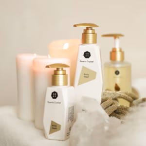 anas douchegel, bodywash en olie. daarnaast staan 3 kaarsen die brengen in de kleur zacht roze en een groot stuk bergkristal.