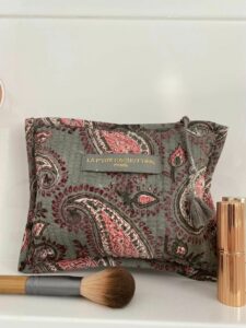Make-up tas grijs blokprint in de kleuren grijs, roze, crème wit van het merk La p'tite Cachottière. De toilettas staat op een wastafel er staan wat make-up artikelen naast.