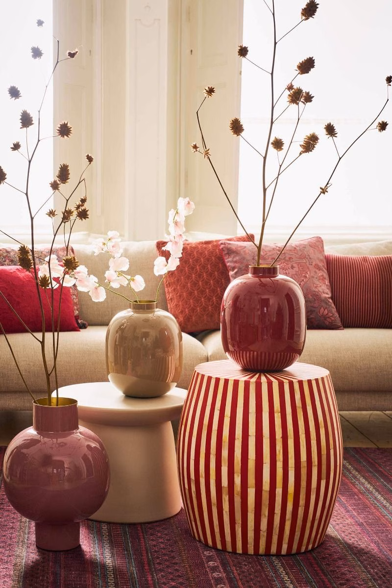 Woonkamer met vazen van Pip studio in de kleuren roze, rood, zandkleur. Op de achtergrond een bank met sierkussens in de kleuren rood en roze van het label Pip studio.