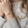 Vrouw draagt armband en broche met een roodborstje van het merk Fable England.