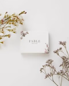 Witte Cadeauverpakking met aan de randen bloemen van Fable England waarin de gouden ring met muisje wordt verpakt.