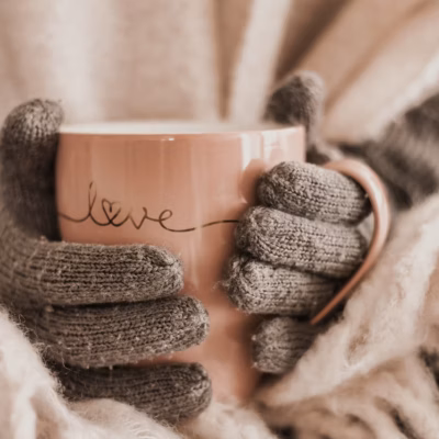 Vrouw met warme handschoenen houdt een beker vast met de tekst 'Love', terwijl de afbeelding verwijst naar het thema: 'Winterdip? Deze tips helpen.