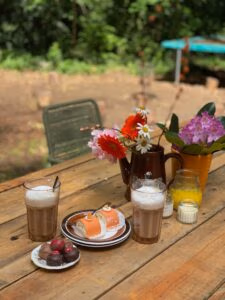 Cappuccino en gebak op de houtentafel van het Hut16 boshuis waar het self-care weekend in het bos wordt gegeven.