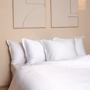 Mooi bed opgemaakt met het Coco & Cici luxe beddengoed wit in een slaapkamer met pasteltinten voor een serene en luxe uitstraling.