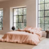 Coco & Cici Tencel beddengoed perzik opgemaakt op een bed in een lichte, moderne slaapkamer.
