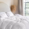 Coco & Cici luxe beddengoed wit, opgemaakt op een tweepersoonsbed in een licht slaapkamer.
