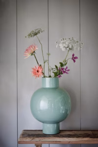 Grote pastelgroene vaas van Pip Studio met bloemen, geplaatst op een houten tafeltje voor een stijlvol interieur.