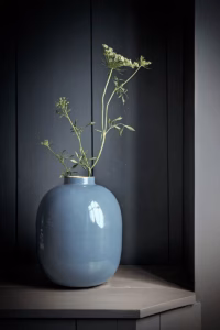 Blauwe Pip Studio vaas met bloemen op tafel in een sfeervolle, donker ingerichte kamer.