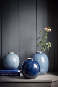 Verschillende blauwe Pip Studio vazen in een donker interieur, één met een bloeiende tak.