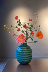Pip Studio gestreepte groene metalen vaas, gestyled met prachtige bloemen op een tafel.