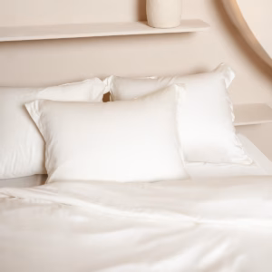 Opgemaakt bed met Coco & Cici Luxe Beddengoed Crème, inclusief kussens en dekbedovertrek, in een elegante slaapkamer voor een luxe slaapervaring.