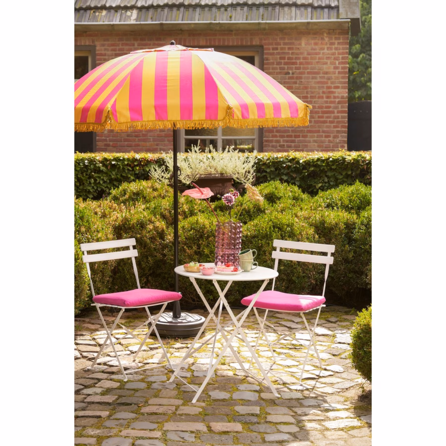 Geel-roze parasol met franjes in tuinsetting – gestyled met tuinmeubilair en zomerse sfeer.
