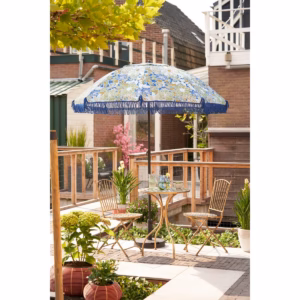 Blauwe parasol met bloemen, gestyled in de tuin met tuinmeubelen en accessoires.