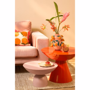 Sierkussen met sinaasappel van Mica Decorations, gestyled op een roze bank met oranje en roze tafeltjes en woonaccessoires van Mica Decorations een frisse, speelse uitstraling.