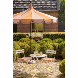 Bruine parasol met franjes van In The Mood Collection in een tuinsetting met twee stoelen en een tafeltje.