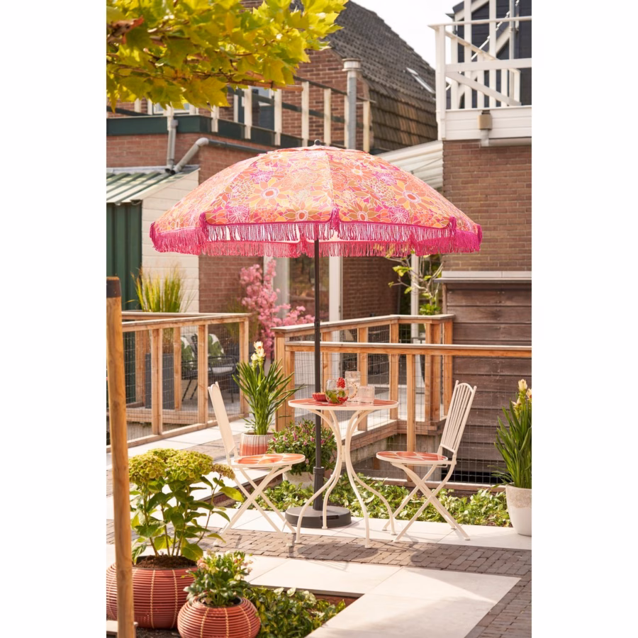 Roze parasol met hartjes in de tuin, gestyled met buitenmeubilair en zomerse accessoires.