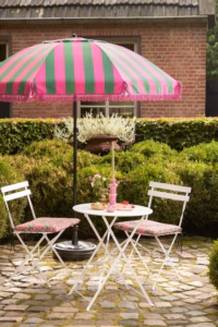 Groen-roze parasol gestyled in een tuin met tuinmeubilair en zomerse sfeer.
